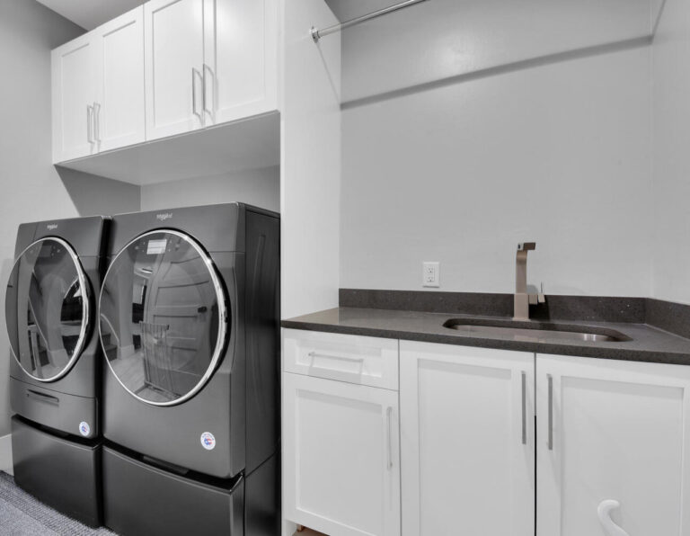 Laundry room with custom white cabinets with utility sink and black stainless steel washer and dryer